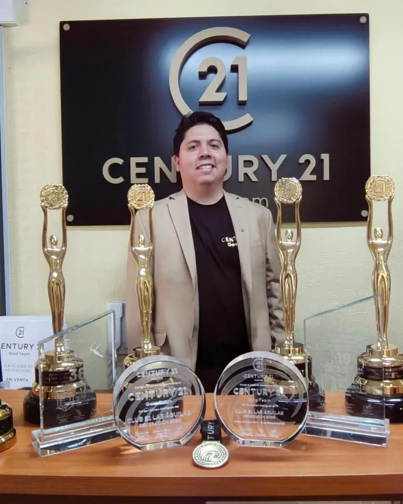 Carlos Franco en la oficina Century 21 Gold Team junto a sus trofeos y reconocimientos